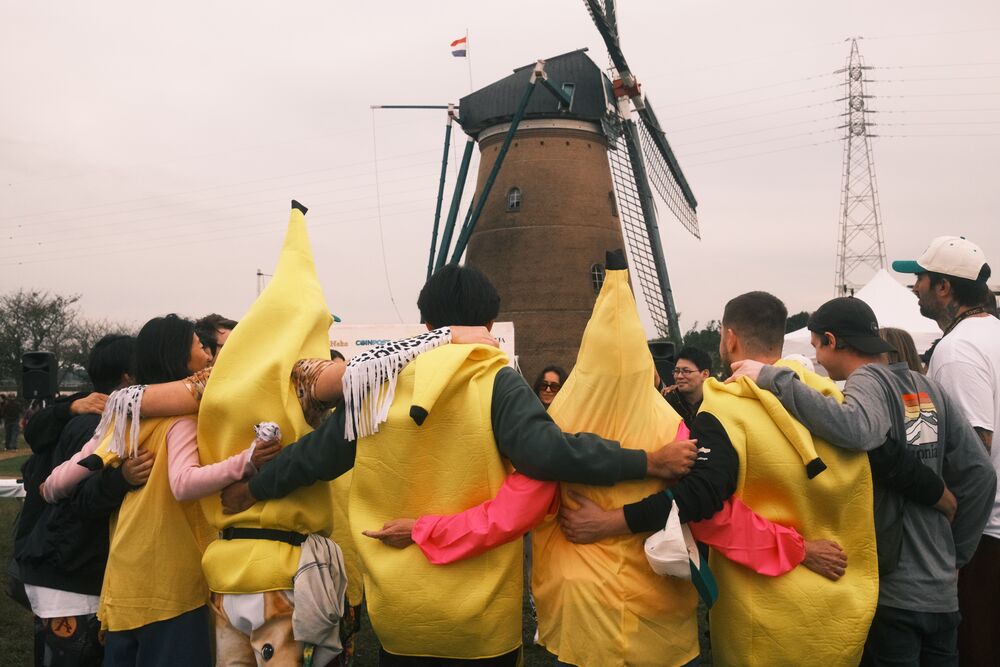 Fans in banana costumes hugging in a circle in front of the windmill